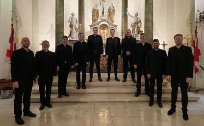 Auf dem Foto sieht man die zehn Sänger von Principium Canti in ihren schwarzen Anzügen nach ihrem Auftritt vor dem Altar der Röllbacher Pfarrkirche.